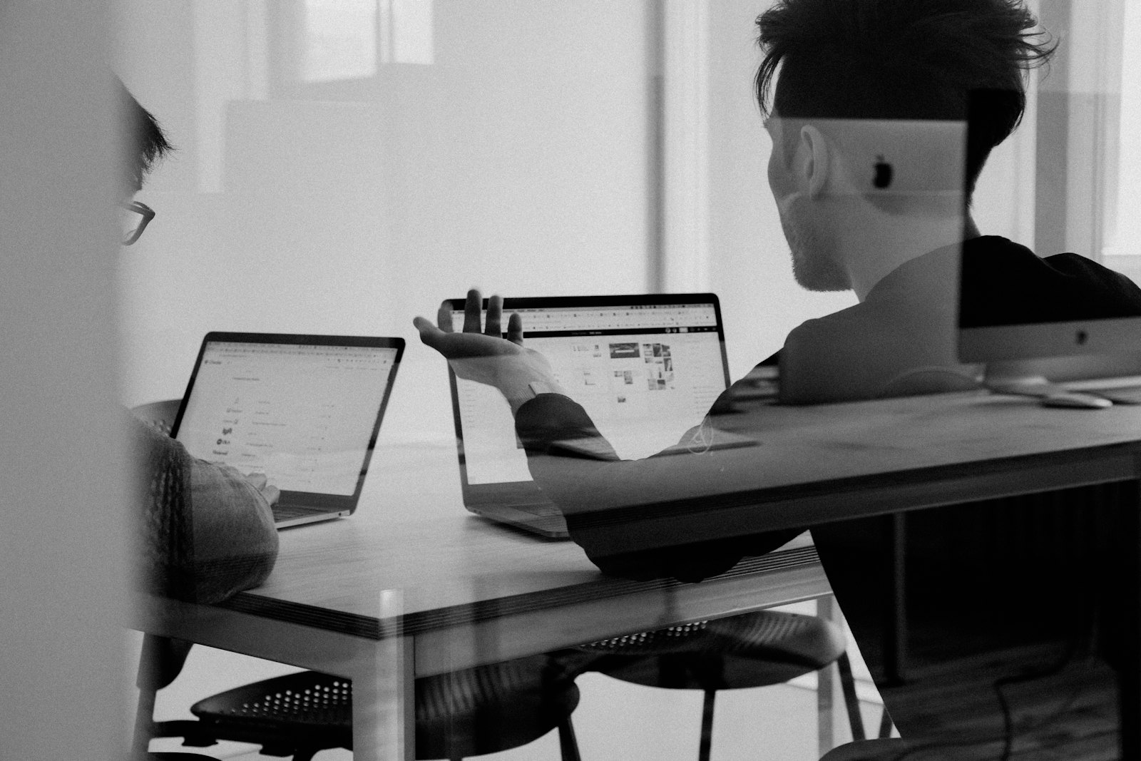 Two people reviewing work together at their laptops